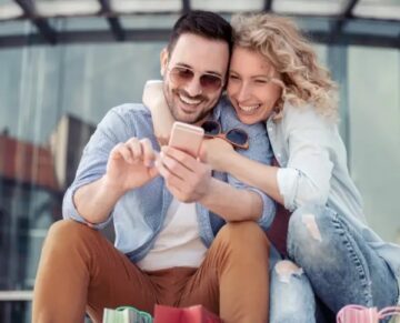 A smiling couple browsing a phone while shopping